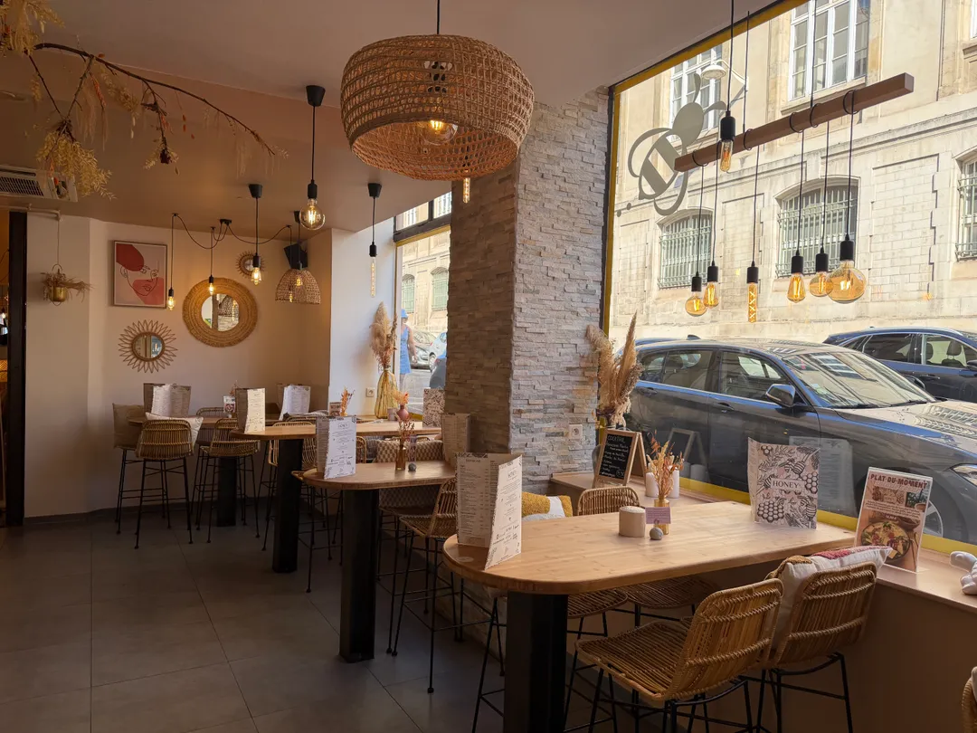 Salle du restaurant Honey à Nancy, tables en rotin et suspensions